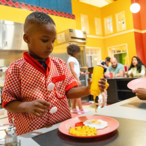 Kid wearing chef apron cooking in diner