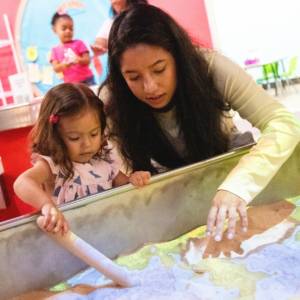 Kid and caregiver playing at sand table