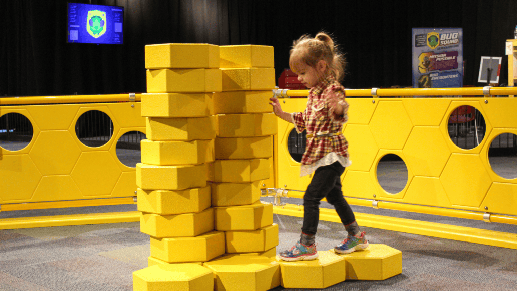 Child playing in Bug Squad exhibit; building with honeycombs