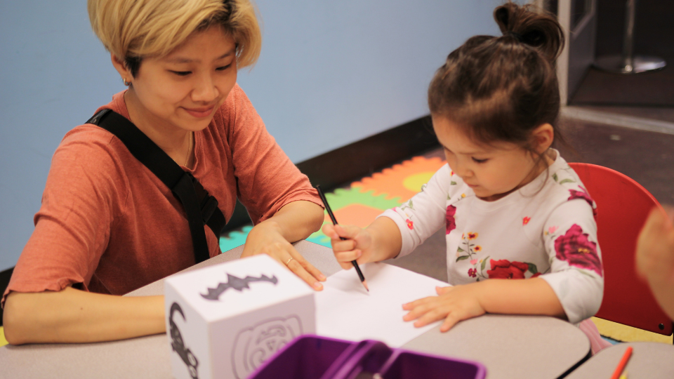Child and caregiver drawing together